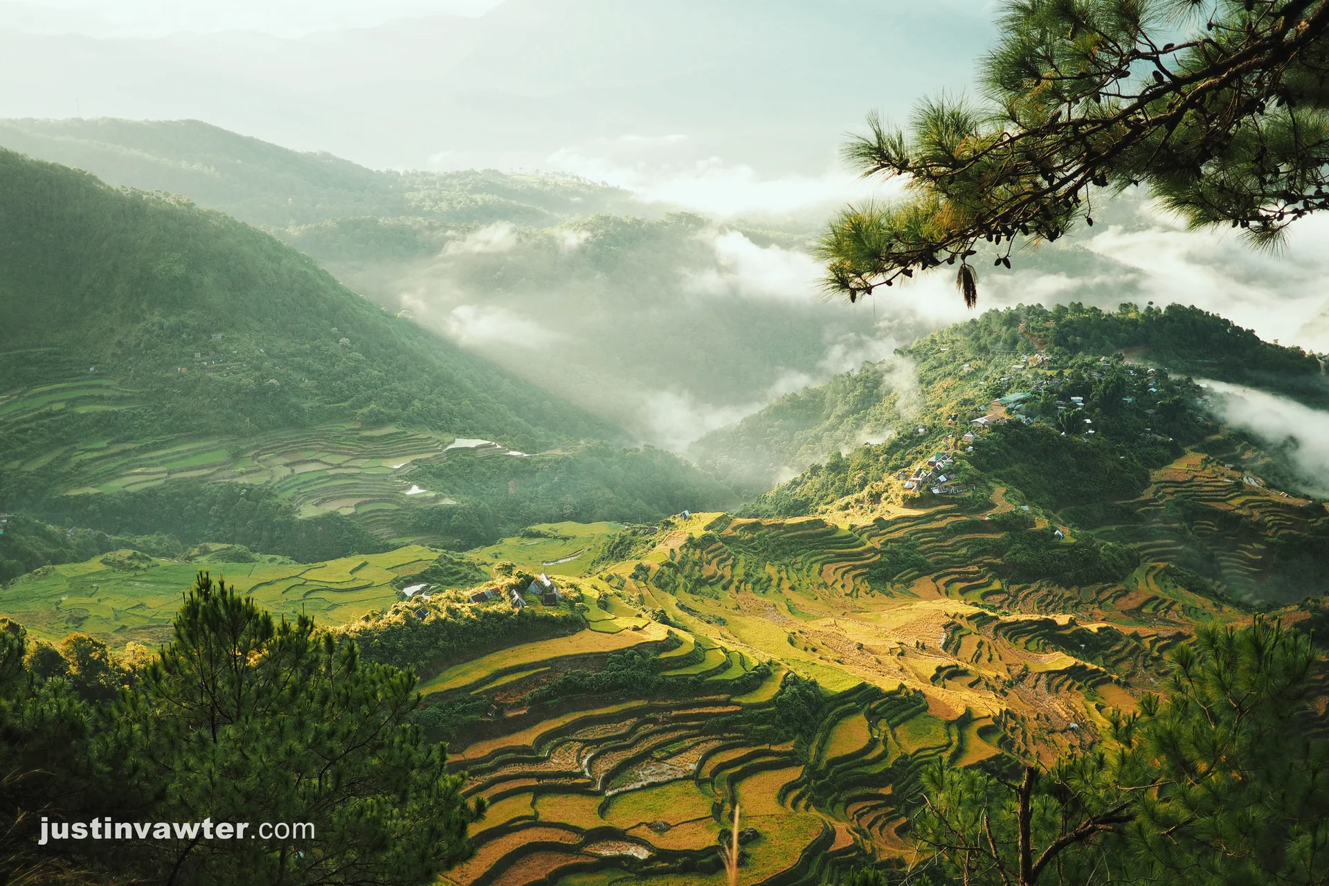 Sunlit rice terraces and misty mountain villages seen from Mount Kupapey